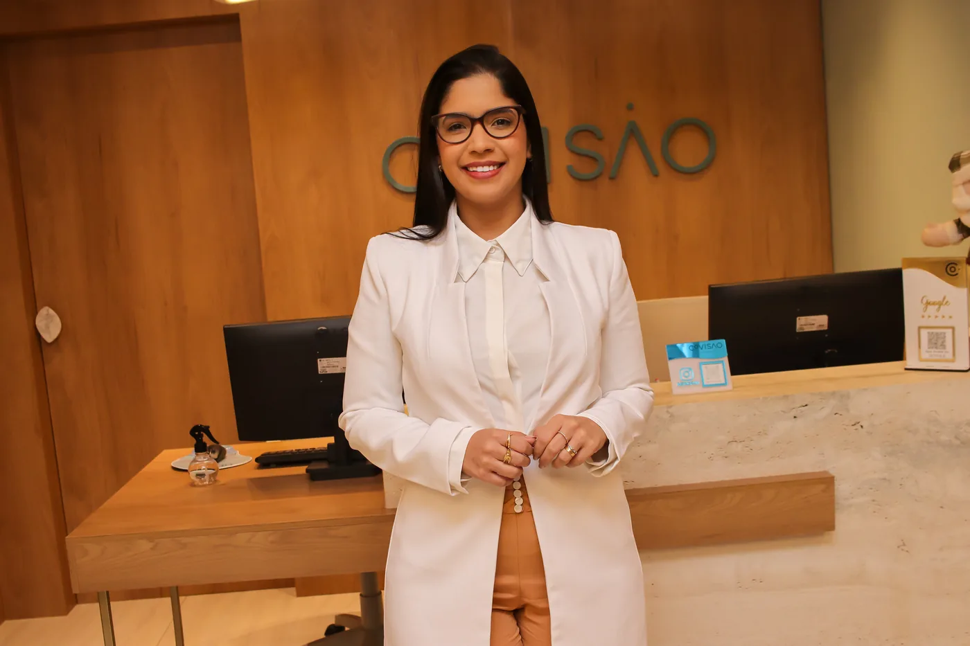 Dra. Ana Luiza Figueirôa na recepção da clínica, ambiente claro com acabamento em madeira